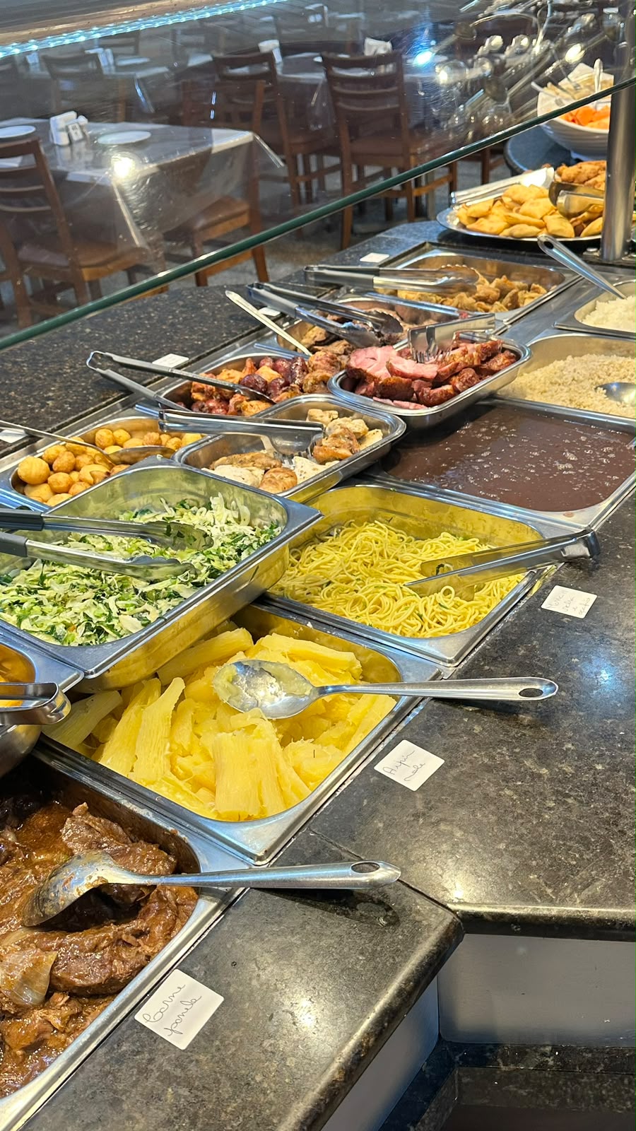 Buffet com massas, aipim, carne de panela e pratos quentes